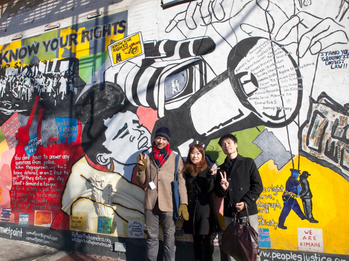 a group of people standing next to a graffiti covered wall