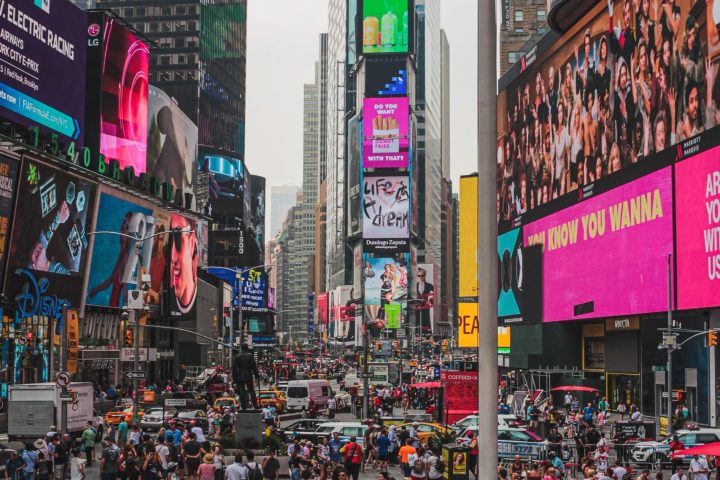 a group of people walking down a busy city street with Times Square in the background